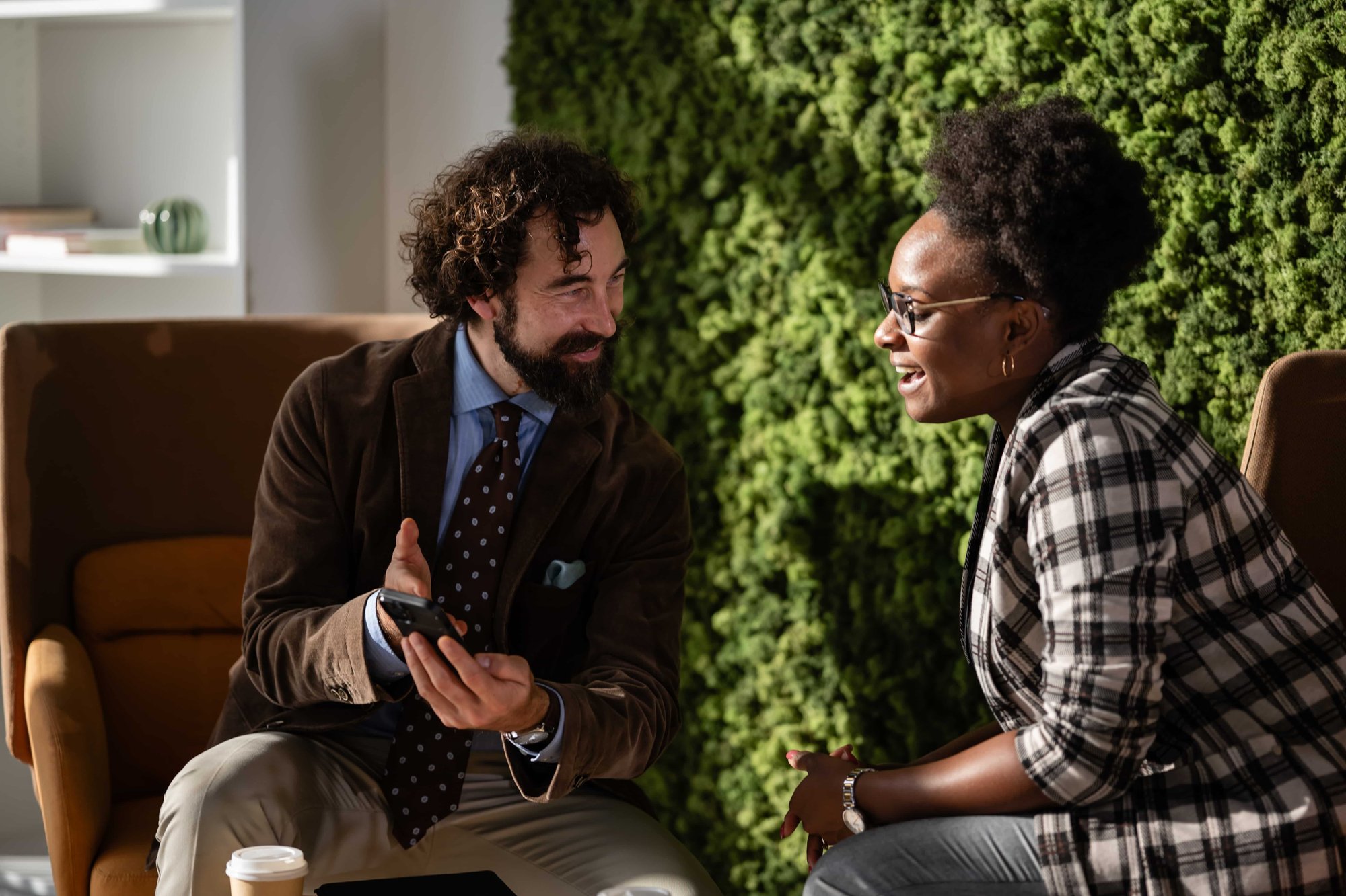 Business colleagues collaborating using smartphone in open office